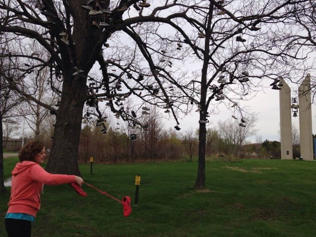May 2014 graduate, Elizabeth Smeaton, continuing the tradition of tossing her shoes into Shoe Tree II.